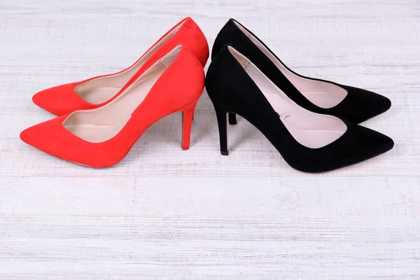 Sapatos femininos vermelhos e pretos bonitos em fundo de madeira — Fotografia de Stock