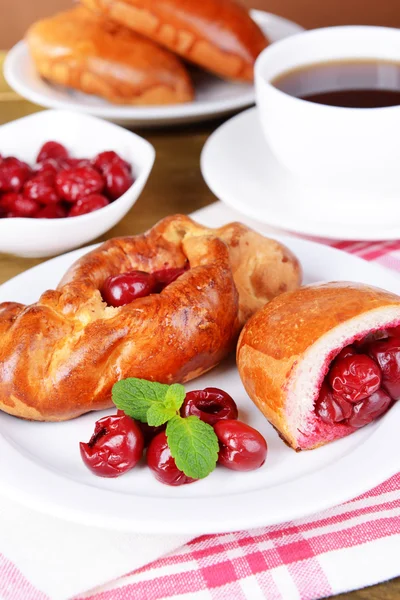 Fresh baked pasties with cherry on plate on table close-up — Stock Photo, Image