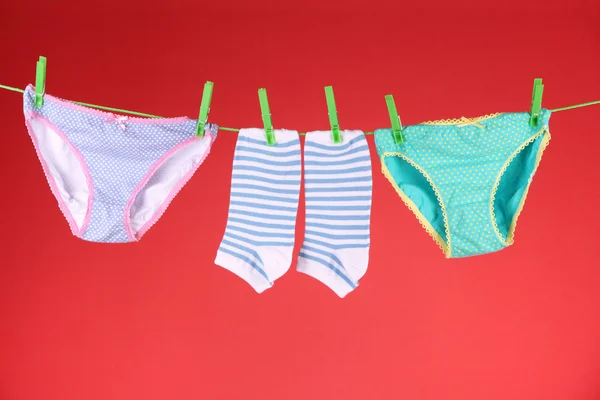 Babykleidung hängt an der Wäscheleine, auf farbigem Hintergrund — Stockfoto