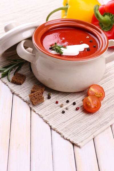 Вкусный томатный суп и овощи на деревянном столе — стоковое фото