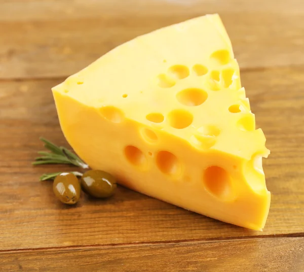 Morceau de fromage aux olives vertes, sur fond de bois — Photo