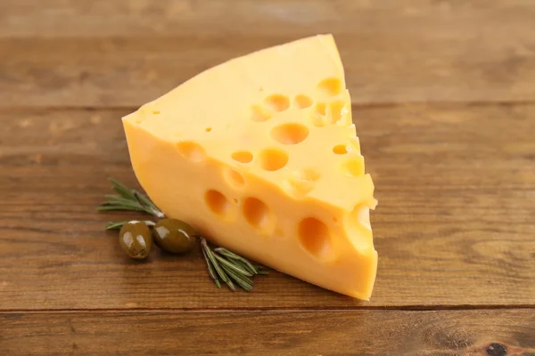 Stück Käse mit grünen Oliven, auf Holzgrund — Stockfoto