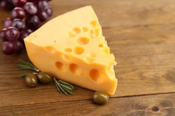 Morceau de fromage aux olives vertes, sur fond de bois — Photo