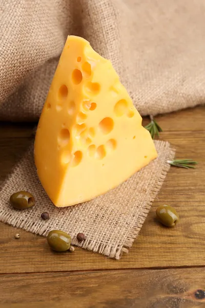 Stück Käse mit grünen Oliven, auf Holzgrund — Stockfoto