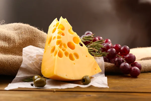 Bit ost på tallrik med gröna oliver, på trä bakgrund — Stockfoto