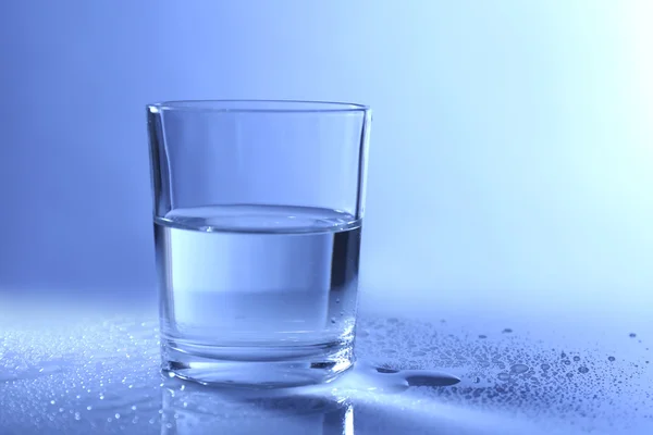 Acqua in vetro, su fondo blu scuro — Foto Stock