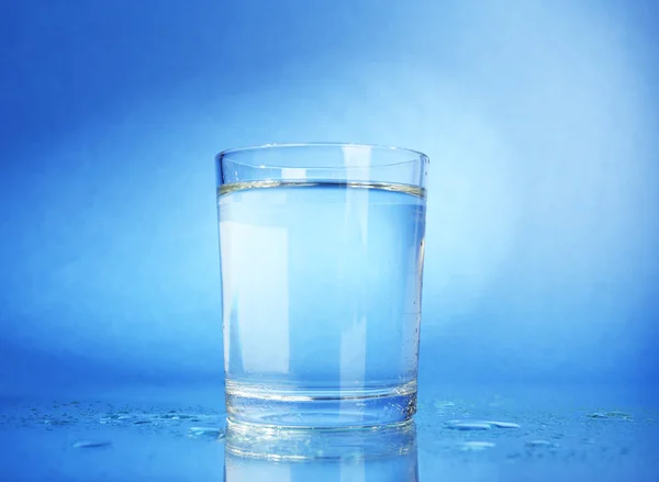 水のガラスでは、濃い青色の背景に — ストック写真