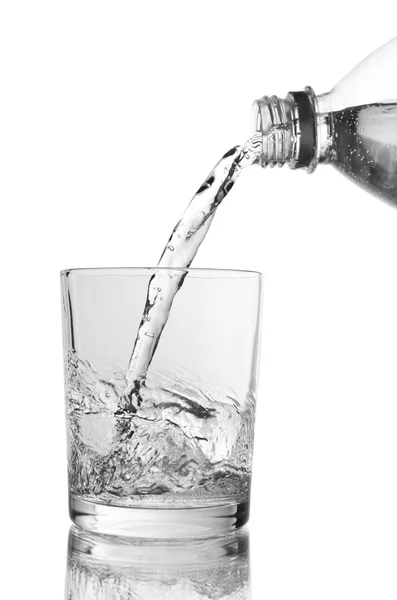 Pour water from bottle into glass, on light blue background — Stock Photo, Image