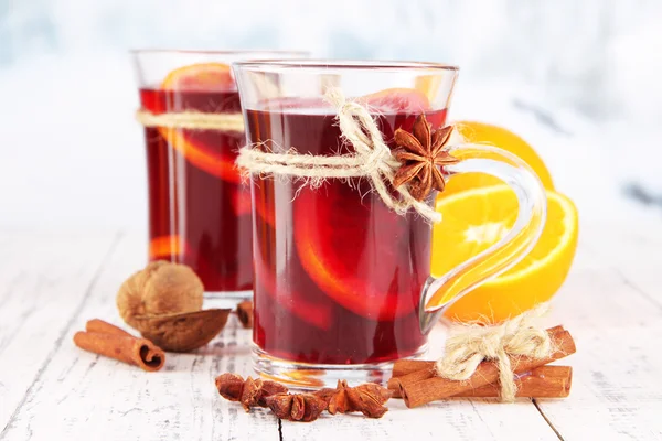 Vinho amontoado com laranjas e especiarias na mesa sobre fundo brilhante — Fotografia de Stock