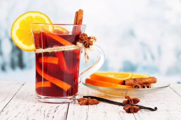 Glühwein met sinaasappels en specerijen op tafel op een heldere achtergrond — Stockfoto