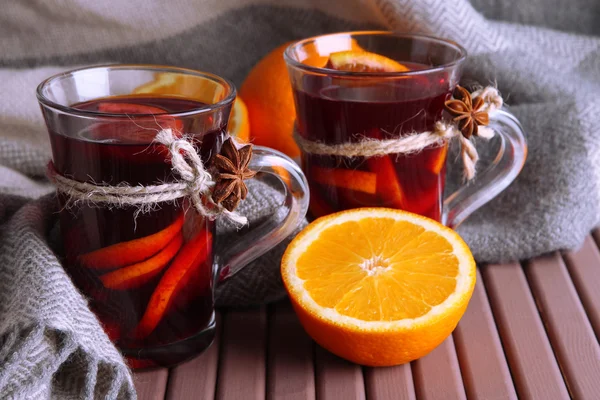 Vino caliente con naranjas en la mesa sobre fondo de tela —  Fotos de Stock