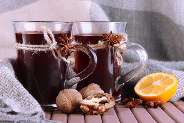 Mulled wine with lemon and nuts on table on fabric background — Stock Photo, Image