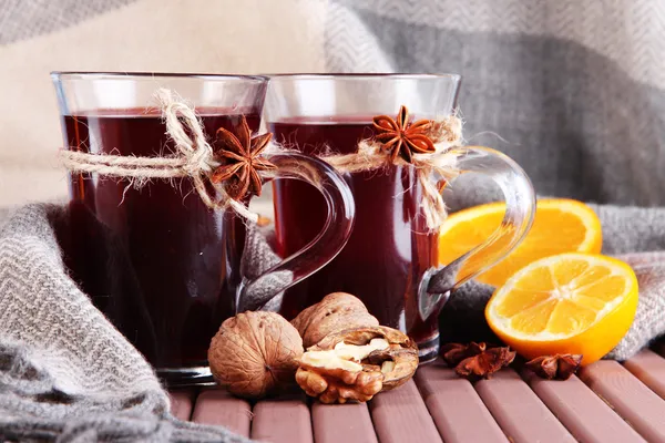 Glühwein met oranje en noten op tafel op stof achtergrond — Stockfoto