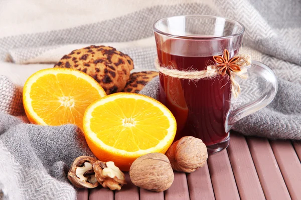 Svařené víno s pomeranče a ořechy na tabulce na pozadí tkaniny — Stock fotografie