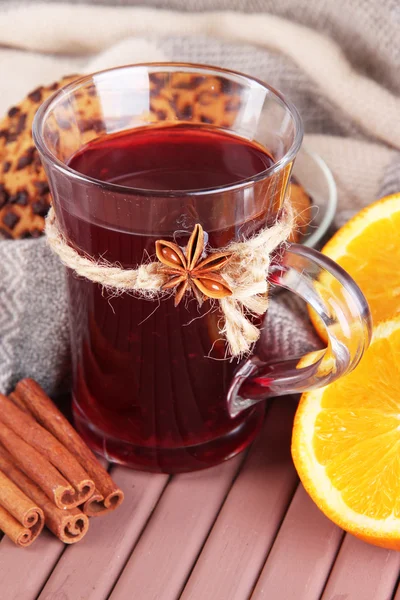 Vino caliente con naranjas y especias en la mesa sobre fondo de tela —  Fotos de Stock