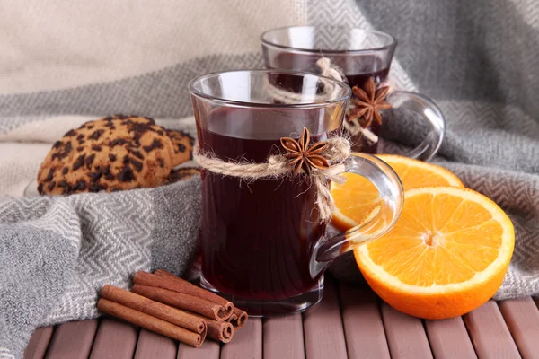 Glühwein met sinaasappels en specerijen op tafel op stof achtergrond — Stockfoto