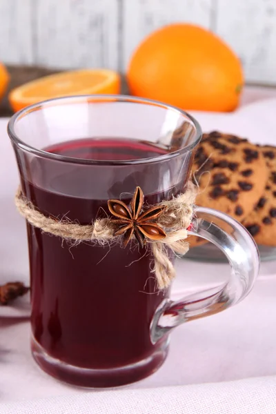 Glühwein met sinaasappels en cookies op tafel op houten achtergrond — Stockfoto