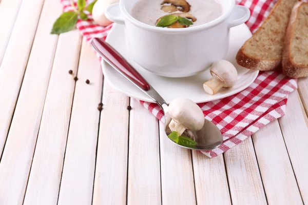 Mushroom soup in white pot, on napkin, on wooden background — Stock Photo, Image