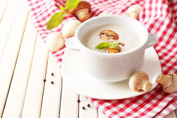 Mushroom soup in white pot, on napkin, on wooden background — Stock Photo, Image