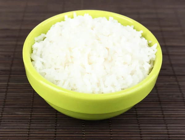 Cooked rice in bowl on bamboo background — Stock Photo, Image
