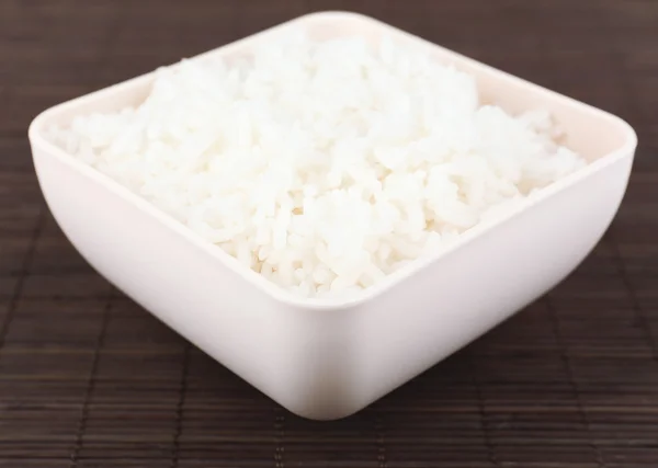 Cooked rice in bowl on bamboo background — Stock Photo, Image