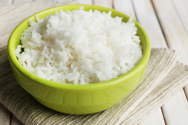 Arroz cozido em tigela no fundo de madeira — Fotografia de Stock