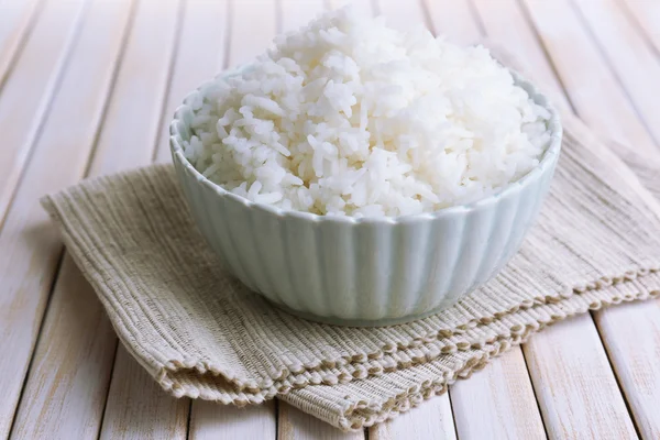 Arroz cozido em tigela no fundo de madeira — Fotografia de Stock