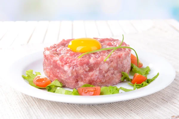 Delicioso bife tartare com gema de ovo na placa na mesa close-up — Fotografia de Stock