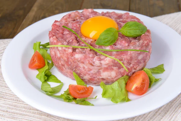 Delicioso bife tartare com gema de ovo na placa na mesa close-up — Fotografia de Stock