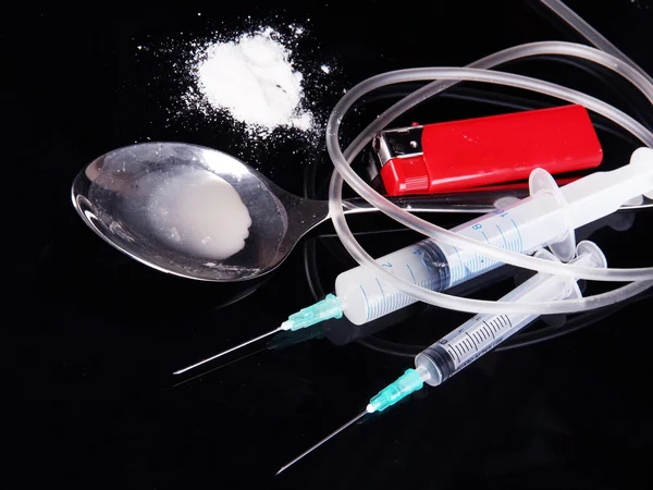 Heroin in spoon and syringes on black background — Stock Photo, Image