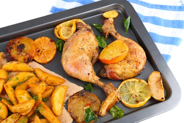 Homemade roasted chicken drumsticks with fried potatoes and vegetables on pan, isolated on white — Stock Photo, Image