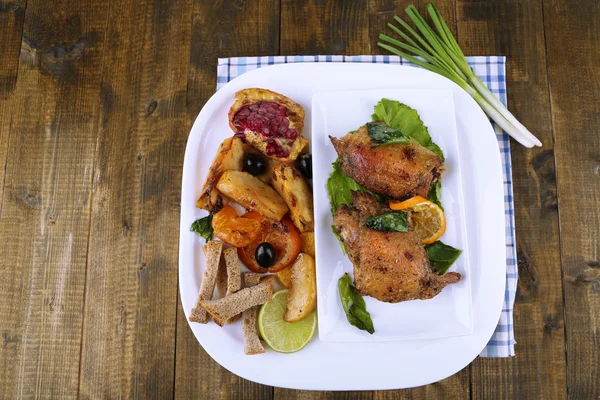 Bâtonnets de poulet frits faits maison avec des légumes dans l'assiette, sur fond en bois — Photo