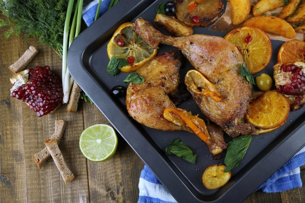 Homemade roasted chicken drumsticks with fried potatoes and vegetables on pan, on wooden background — Stock Photo, Image