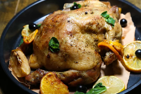 Whole roasted chicken with vegetables on pan, on wooden background — Stock Photo, Image