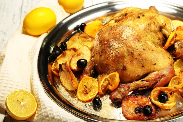 Целый жареный цыпленок с овощами на подносе, на деревянном фоне — стоковое фото