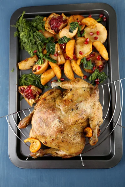 Whole roasted chicken with vegetables and fried potatoes on pan, on color wooden background — Stock Photo, Image