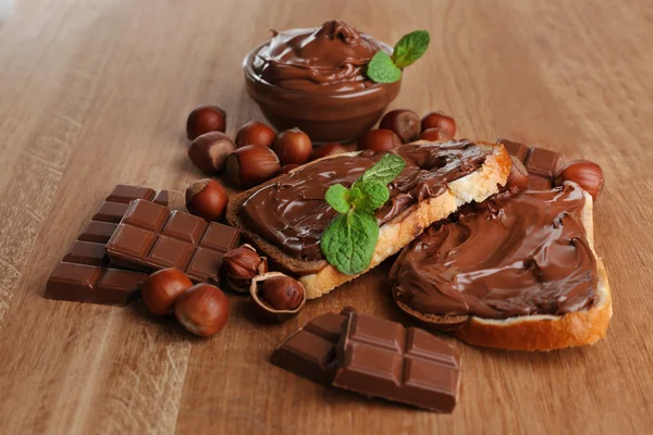 A mogyorós csokoládé terjed a fa háttér édes kenyér — Stock Fotó