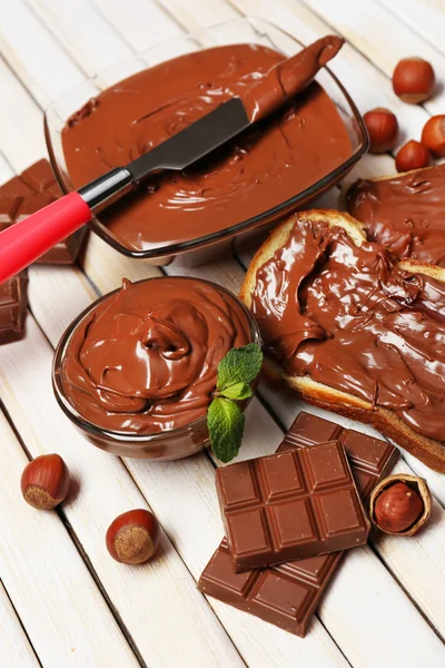 Cioccolato dolce nocciola diffusione con noci intere e menta su sfondo di legno — Foto Stock