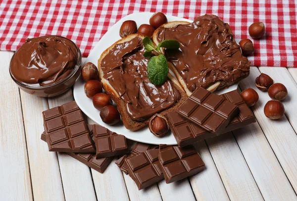 Çikolatalı fındık ahşap zemin üzerine yayılmış sweet ile ekmek — Stok fotoğraf