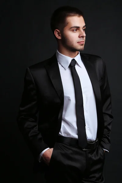 Handsome young man in suit on dark background — Stock Photo, Image