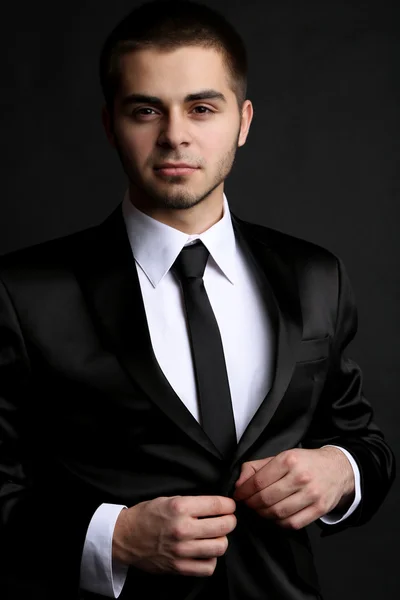 Handsome young man in suit on dark background — Stock Photo, Image