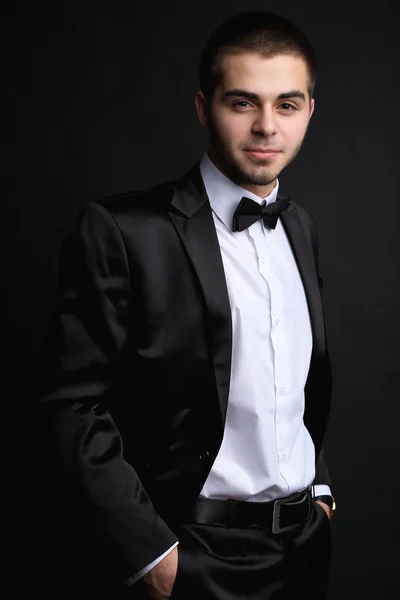 Handsome young man in suit on dark background — Stock Photo, Image