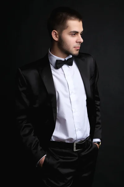 Hombre joven guapo en traje sobre fondo oscuro —  Fotos de Stock