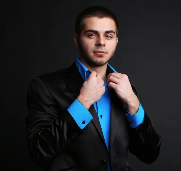 Hombre joven guapo en traje sobre fondo oscuro —  Fotos de Stock