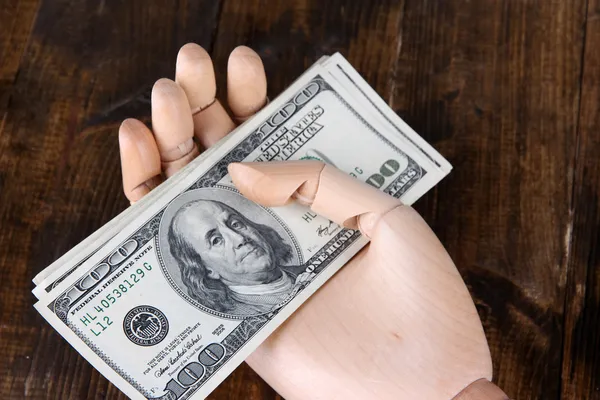 Money in wooden hand, on wooden background — Stock Photo, Image