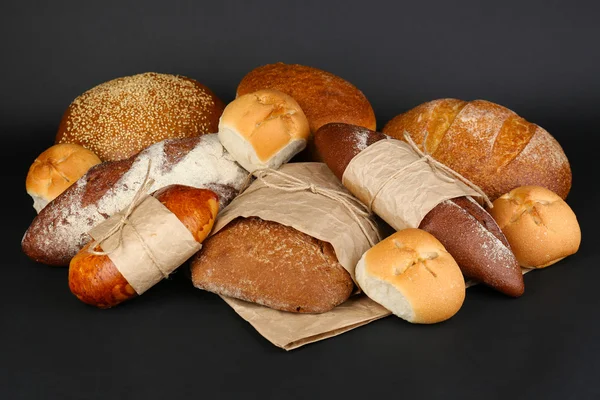 Diferentes tipos de pão no fundo preto, close-up — Fotografia de Stock