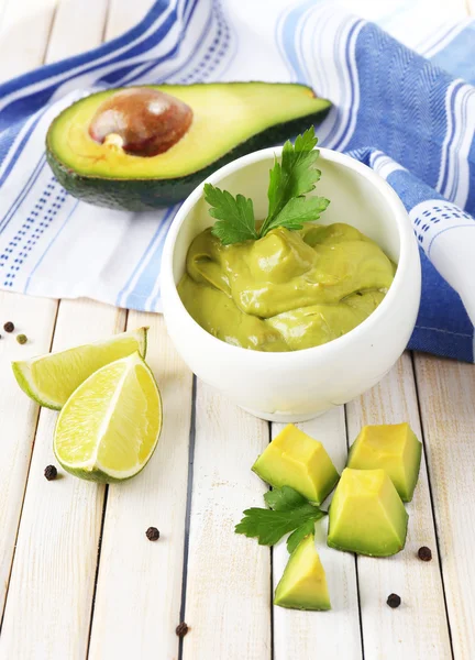 Fresh guacamole in bowl on wooden table — Stock Photo, Image