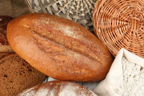 Pan de centeno con harina en la mesa sobre fondo de mimbre —  Fotos de Stock