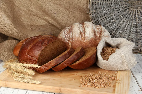 Pane di segale con grani sul tavolo su fondo sacco — Foto Stock