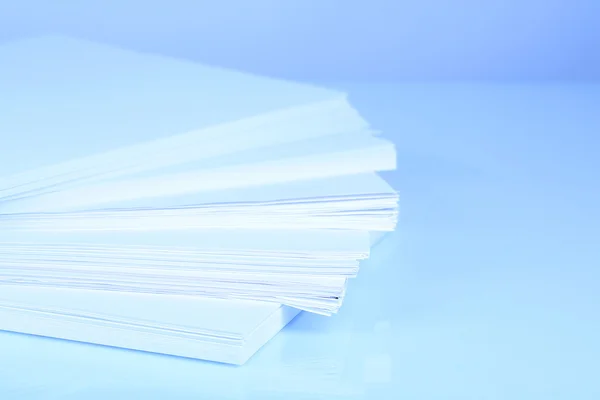 Stack white paper close-up in blue light — Stock Photo, Image